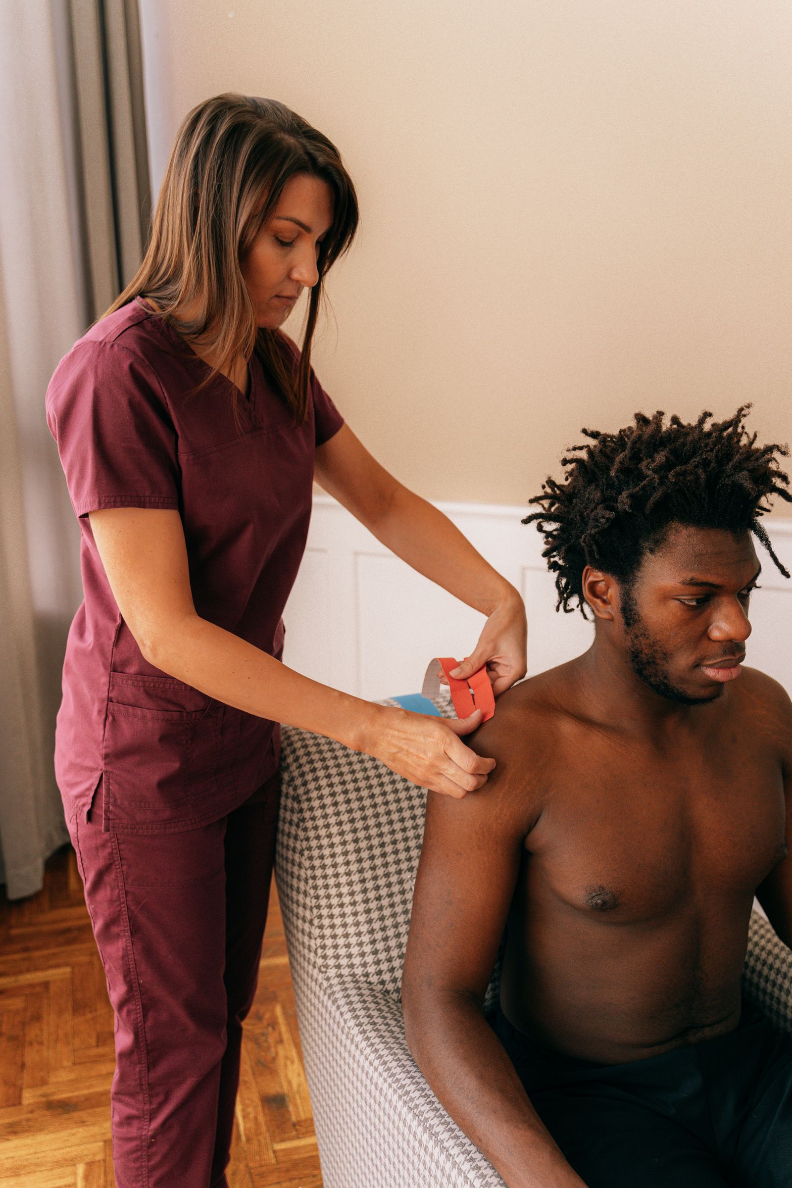 A therapist applying kinesiology tape to an athlete's shoulder