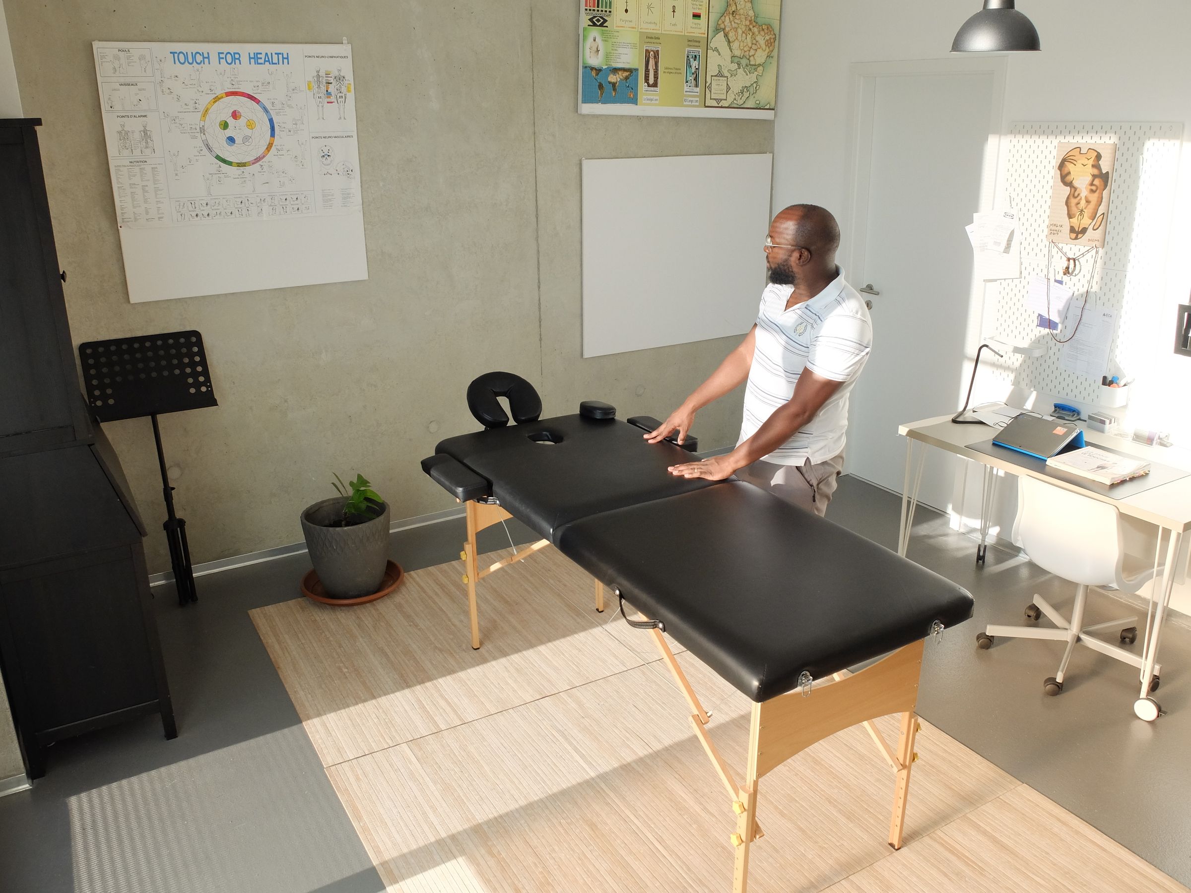 A practitioner beside a treatment table in a sunlit room