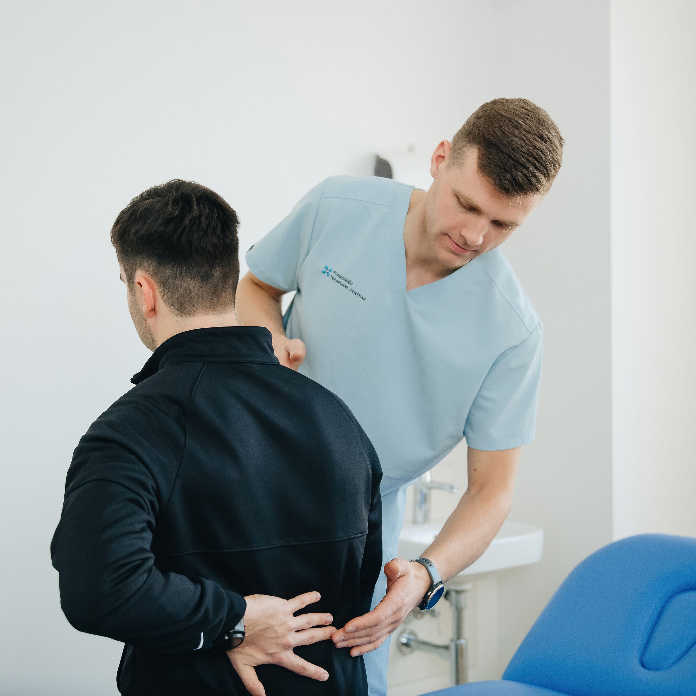A physical therapist assessing a man's lower back