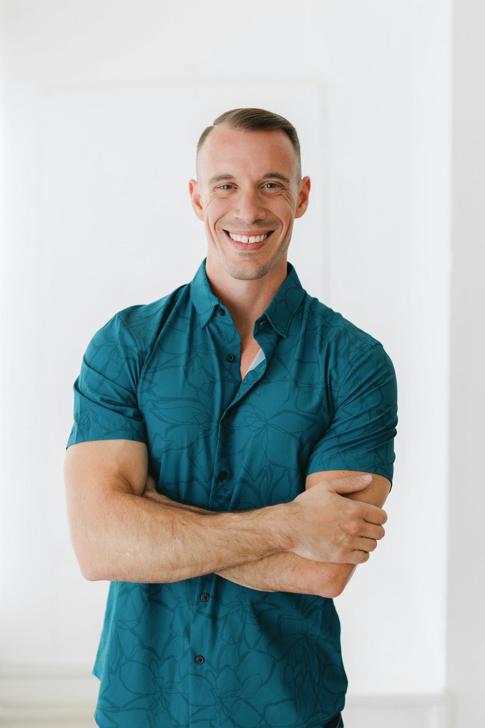 Portrait of a smiling man in a teal shirt with his arms crossed