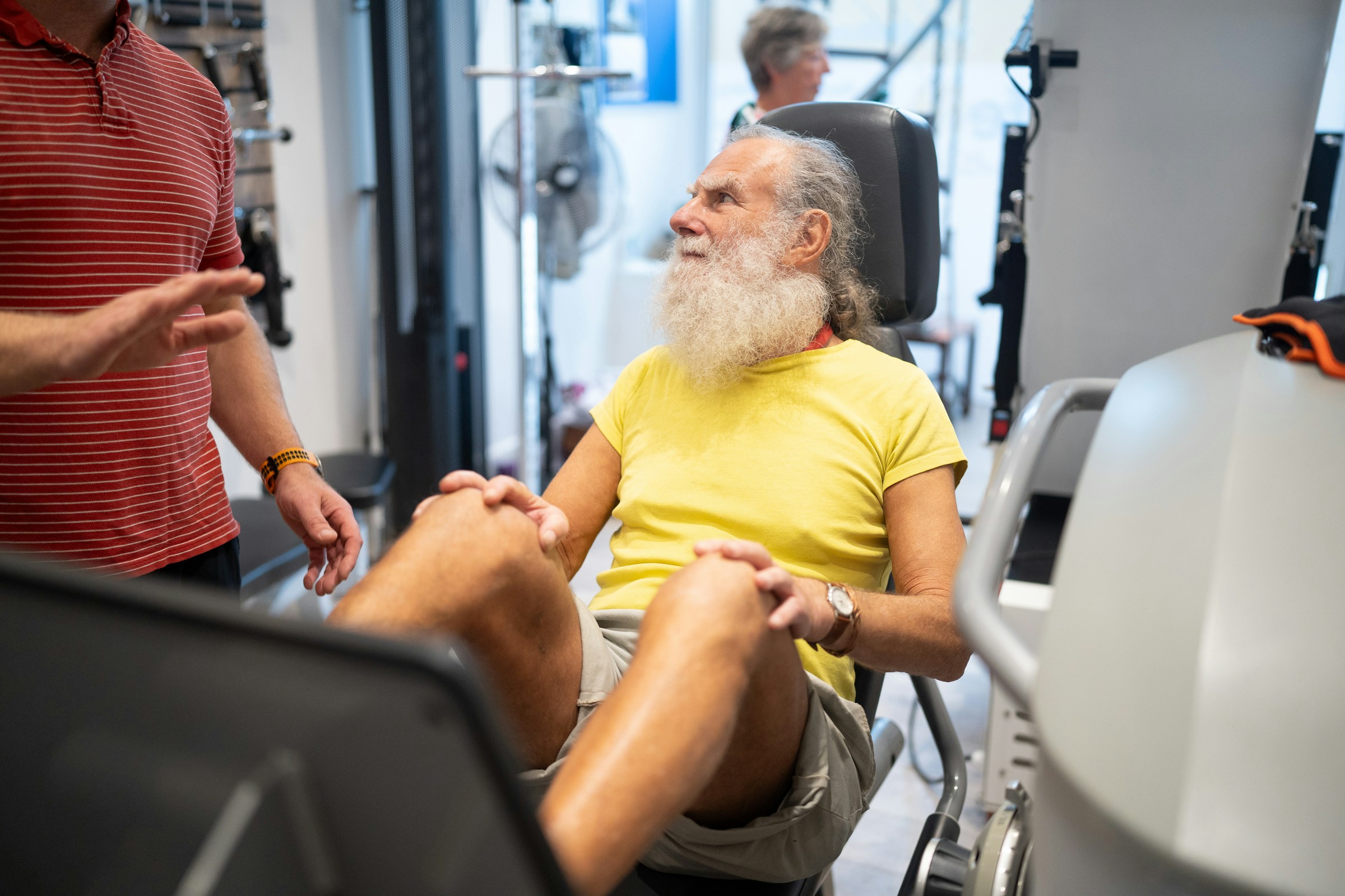 An older man resting between exercises in a rehab gym