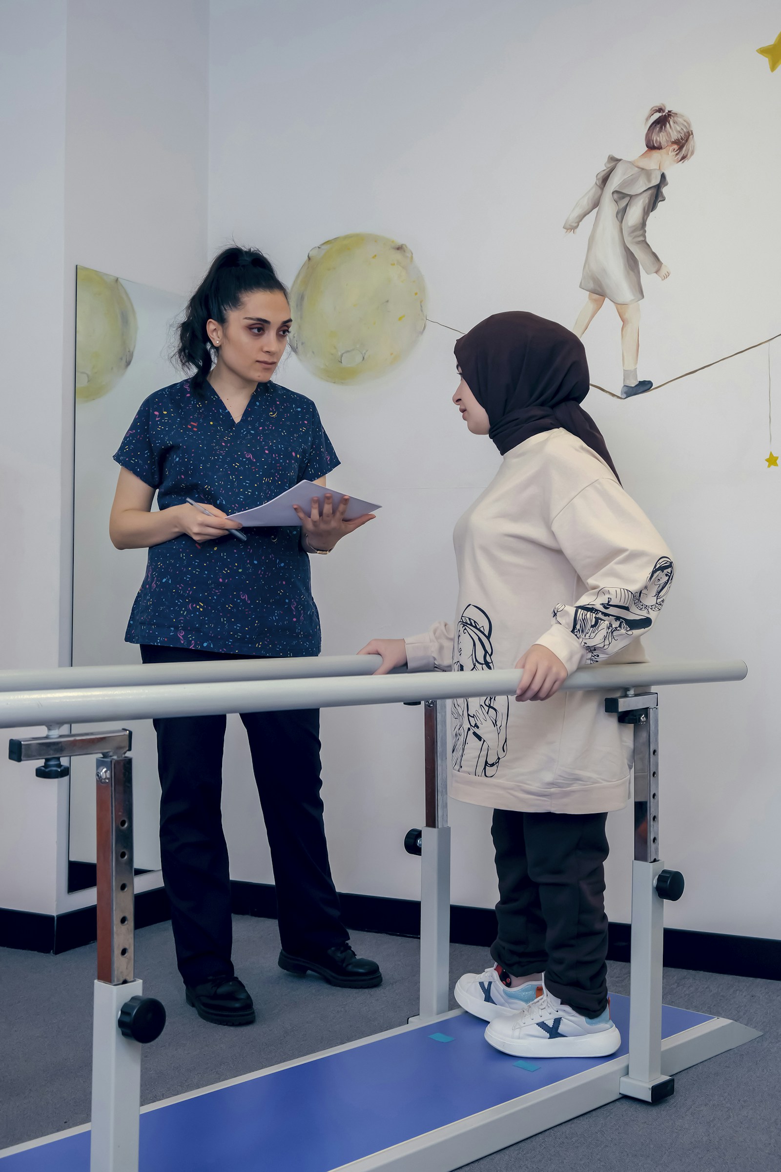 A therapist beside a patient walking between parallel bars