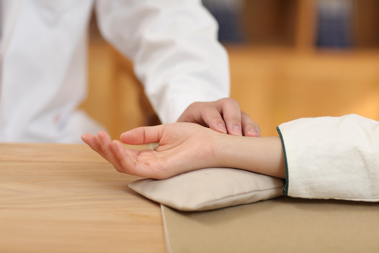 A practitioner's fingertips on a patient's wrist, taking the pulse as in Chinese medicine